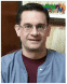 A man wearing glasses and blue scrubs.